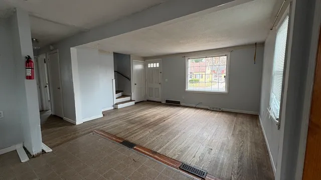 an empty room with wooden floor and windows