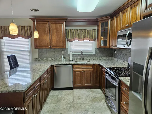 a kitchen with granite countertop a sink a stove and a wooden cabinets
