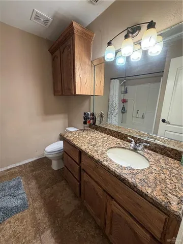 a bathroom with a granite countertop sink a toilet and a mirror