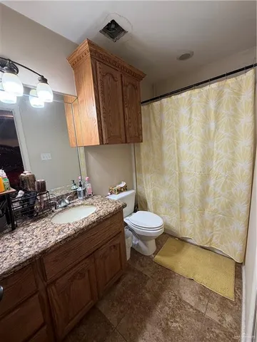 a bathroom with a granite countertop sink a toilet and a mirror