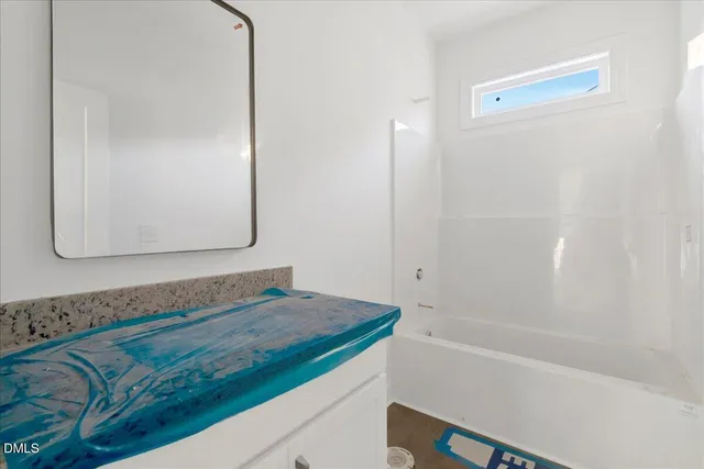a bathroom with a granite countertop tub sink and mirror