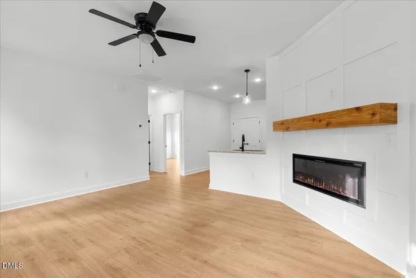 a view of a livingroom with a fireplace a ceiling fan and wooden floor