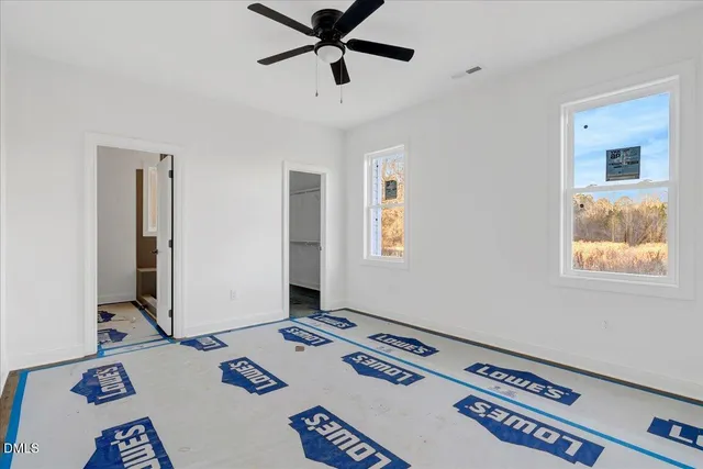 a view of an empty room with window and a ceiling fan