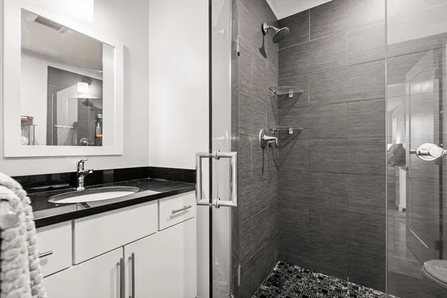 a bathroom with a granite countertop sink a mirror and shower