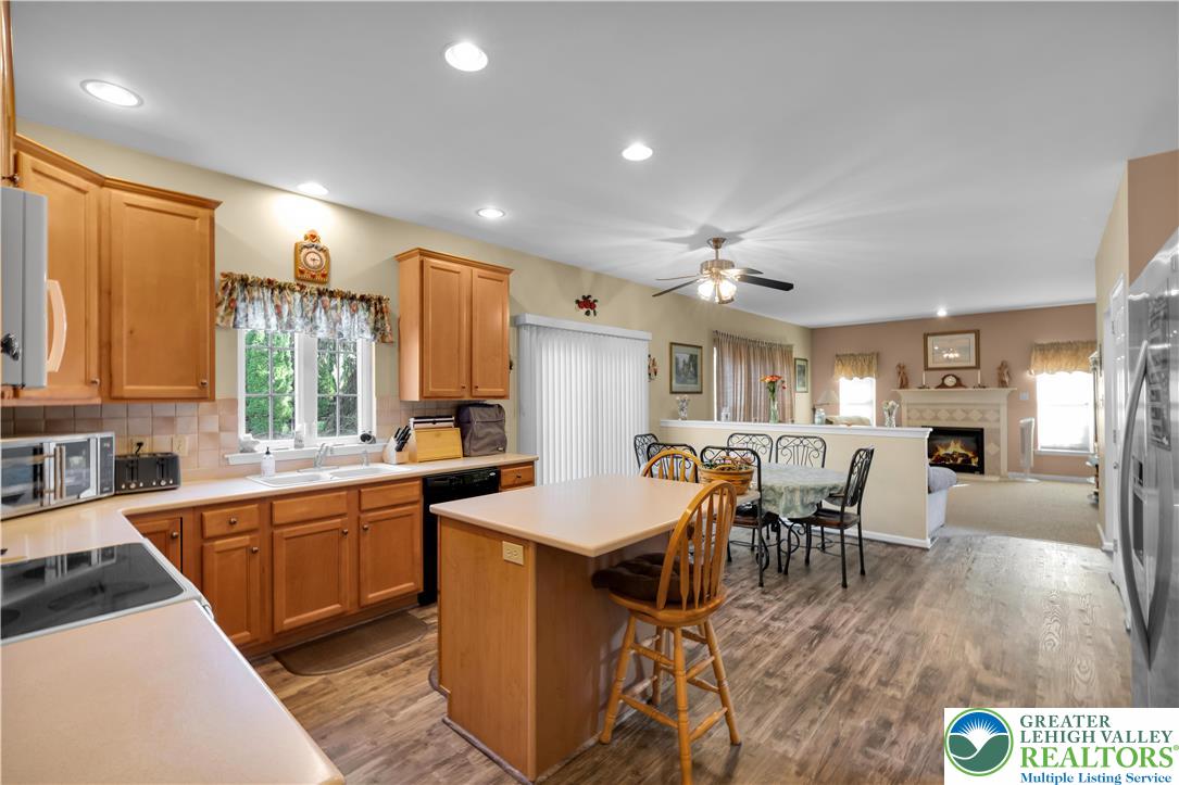 5920 Michael's Crossing Orefield, PA 18069 - Photo 14 of 31 a kitchen with stainless steel appliances granite countertop a stove top oven a sink dishwasher a dining table and chairs with wooden floor