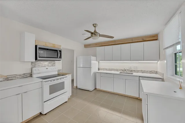 a kitchen with white cabinets and appliances