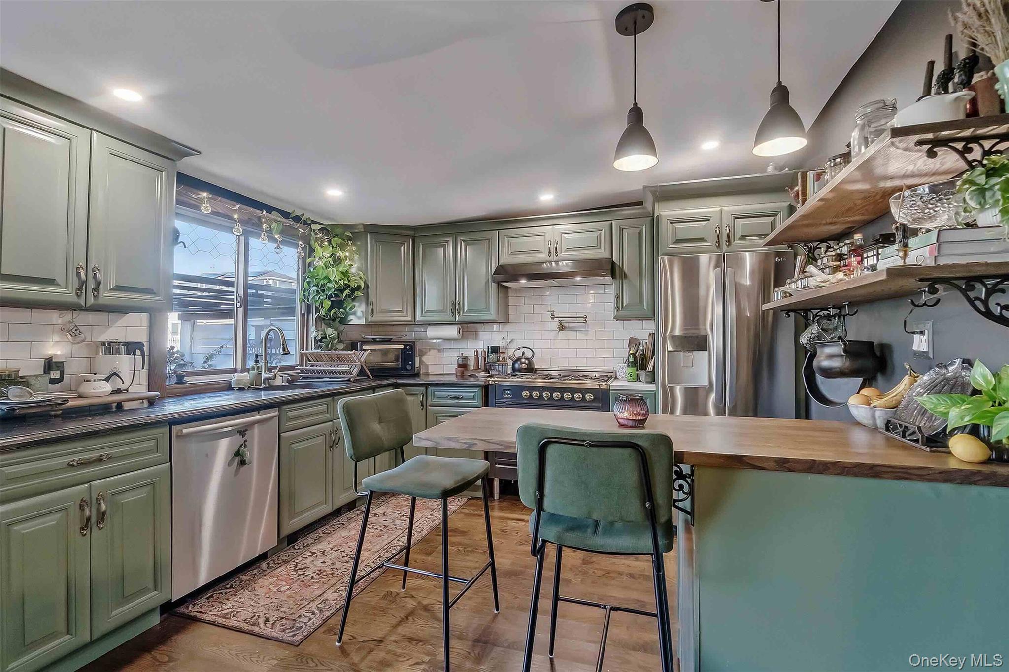 27 West 11th Road Queens, NY 11693 - Photo 10 of 18 Kitchen with green cabinetry, pendant lighting, stainless steel appliances, open shelves, and under cabinet range hood