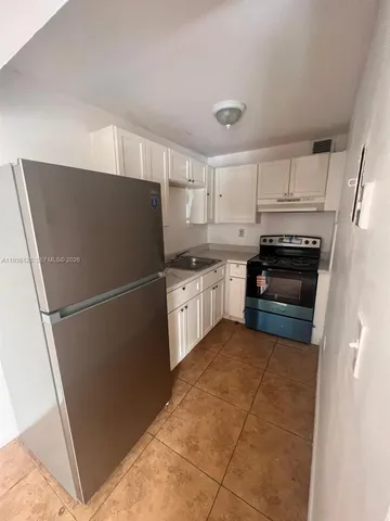 a kitchen with granite countertop a refrigerator and a stove top oven