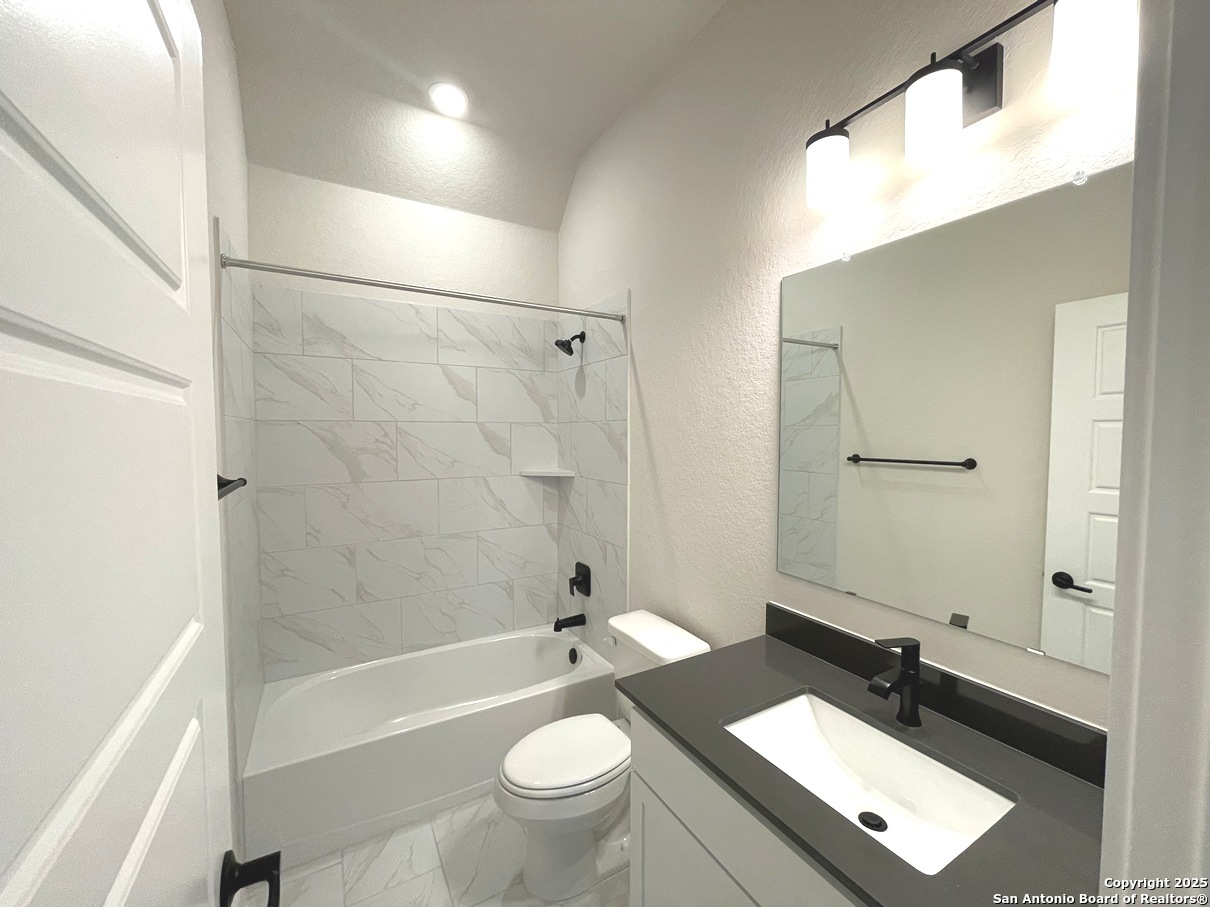 116 Radnor Road New Braunfels, TX 78130 - Photo 13 of 26 a bathroom with a sink a toilet a mirror a bathtub and shower