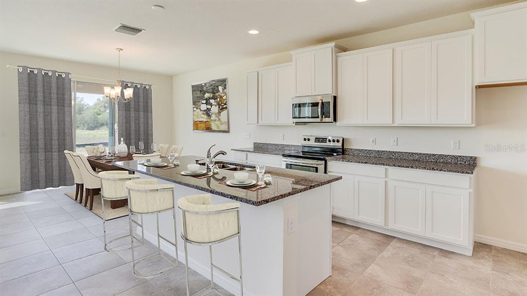 17536 Maple Grv Road Land O Lakes, FL 34638 - Photo 4 of 15 a kitchen with stainless steel appliances kitchen island granite countertop a sink and white cabinets