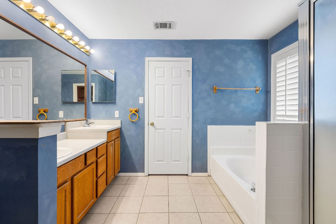 112 Amherst Court Kyle, TX 78640 - Photo 19 of 38 a bathroom with a sink a mirror and a bathtub