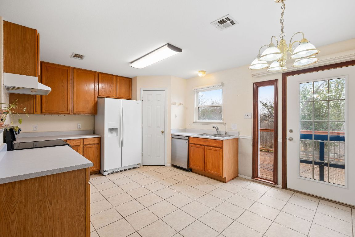112 Amherst Court Kyle, TX 78640 - Photo 10 of 38 a kitchen with stainless steel appliances granite countertop a refrigerator a sink dishwasher a stove with wooden cabinets