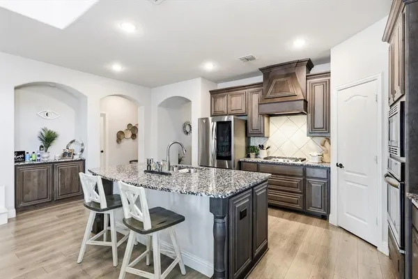 a kitchen with stainless steel appliances granite countertop a kitchen island and chairs in it