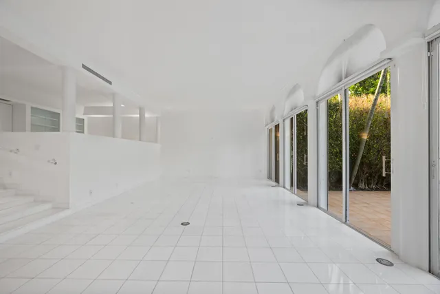 a view of an empty room with windows and chandelier