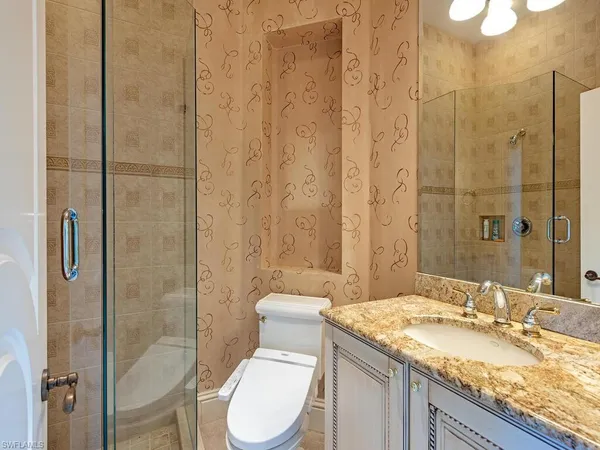 a bathroom with a granite countertop sink toilet and shower