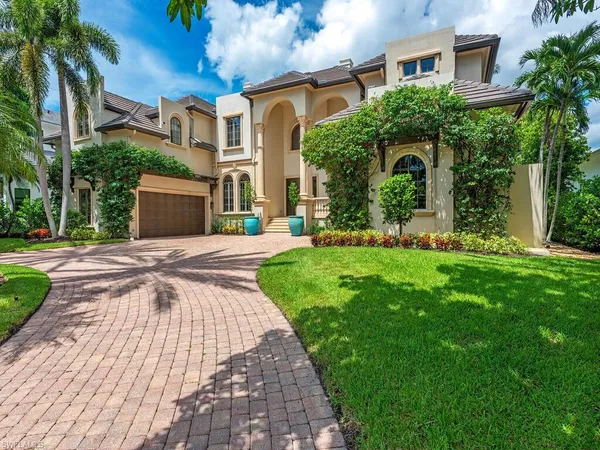 a front view of a house with a yard and potted plants