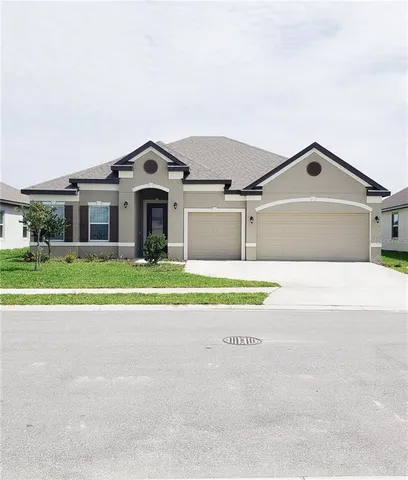 a view of house with a big yard and large trees