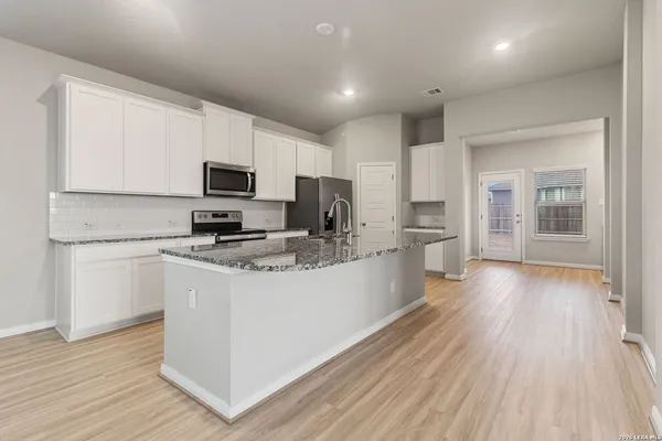 a kitchen with stainless steel appliances granite countertop a stove top oven a sink dishwasher and a refrigerator with wooden floor