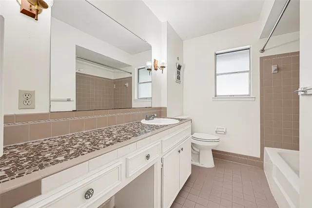 a bathroom with a granite countertop sink a toilet and mirror
