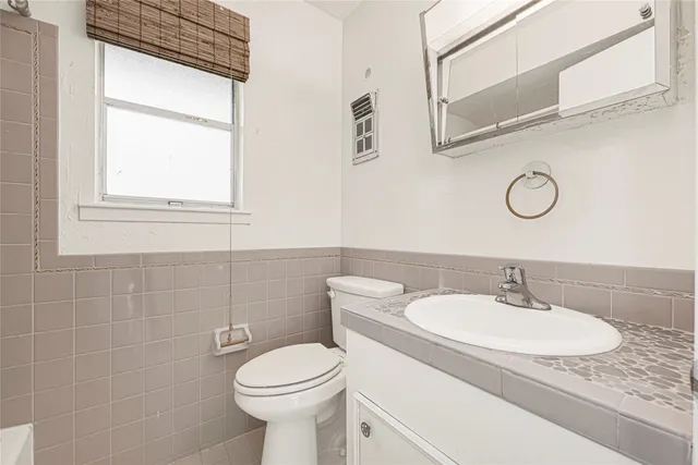 a bathroom with a granite countertop sink toilet and a mirror