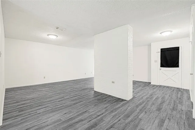 a view of an empty room with wooden floor and mirror