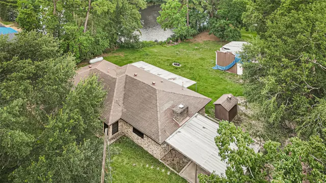 an aerial view of a house with outdoor space and trees all around
