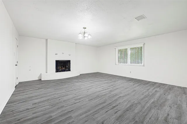 an empty room with wooden floor and chandelier