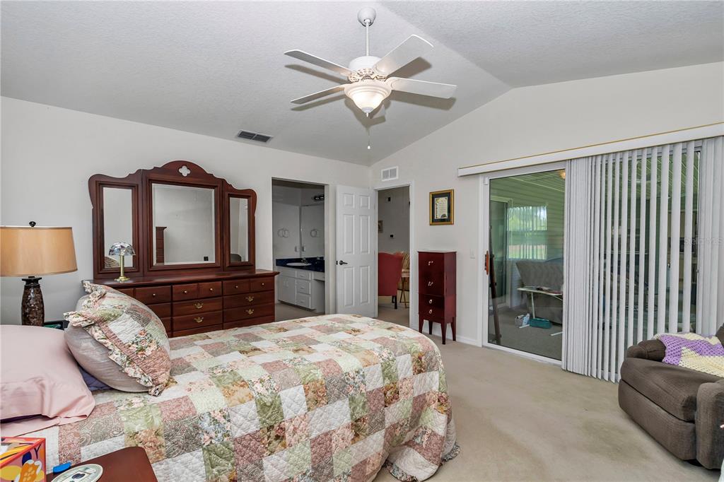 8342 Southwest 65th Avenue Ocala, FL 34476 - Photo 17 of 40 a bedroom with a large bed and a chandelier