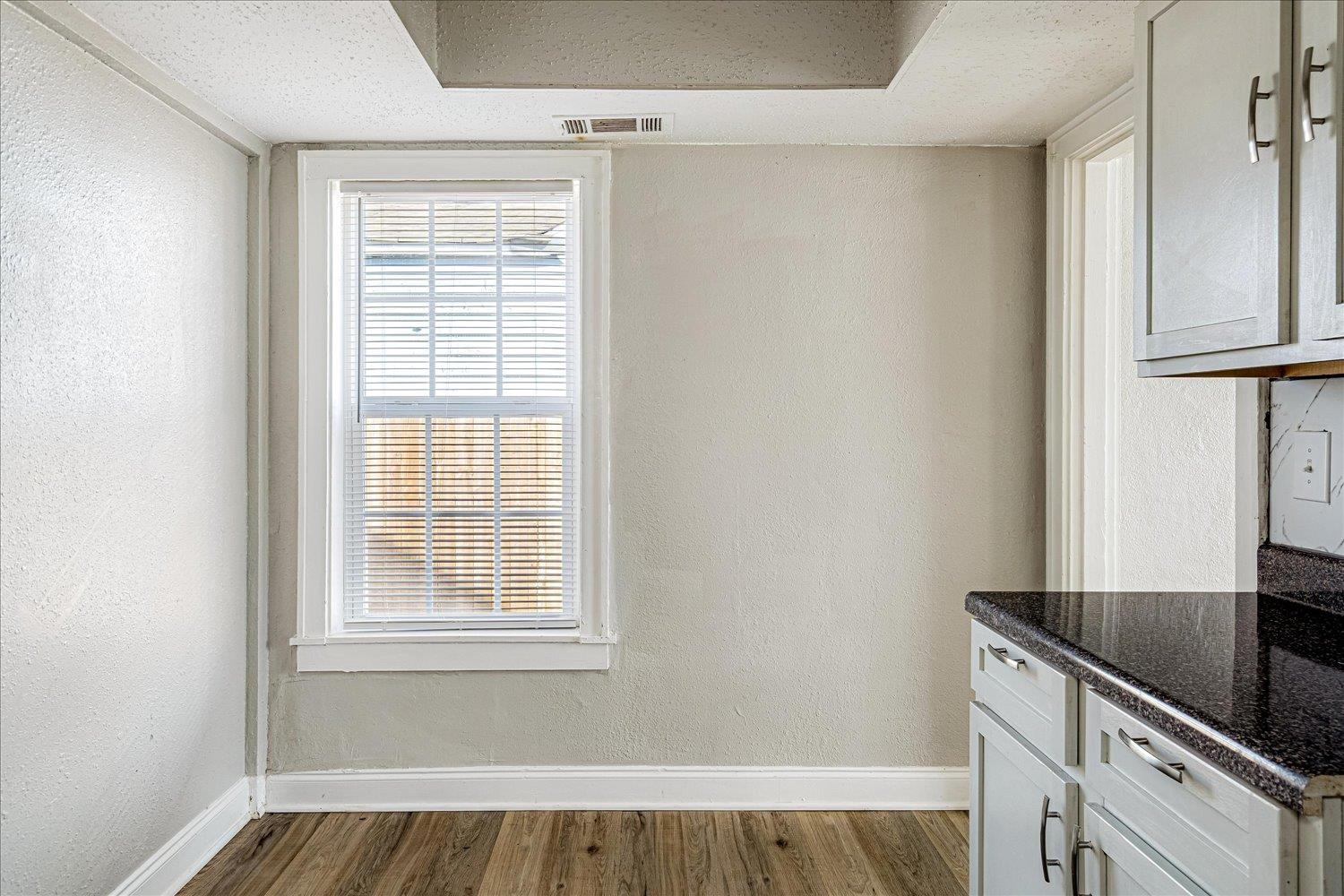 3084 Pershing Avenue Memphis, TN 38112 - Photo 17 of 30 Kitchen with a textured wall, dark stone counters, dark wood-style flooring, and white cabinetry