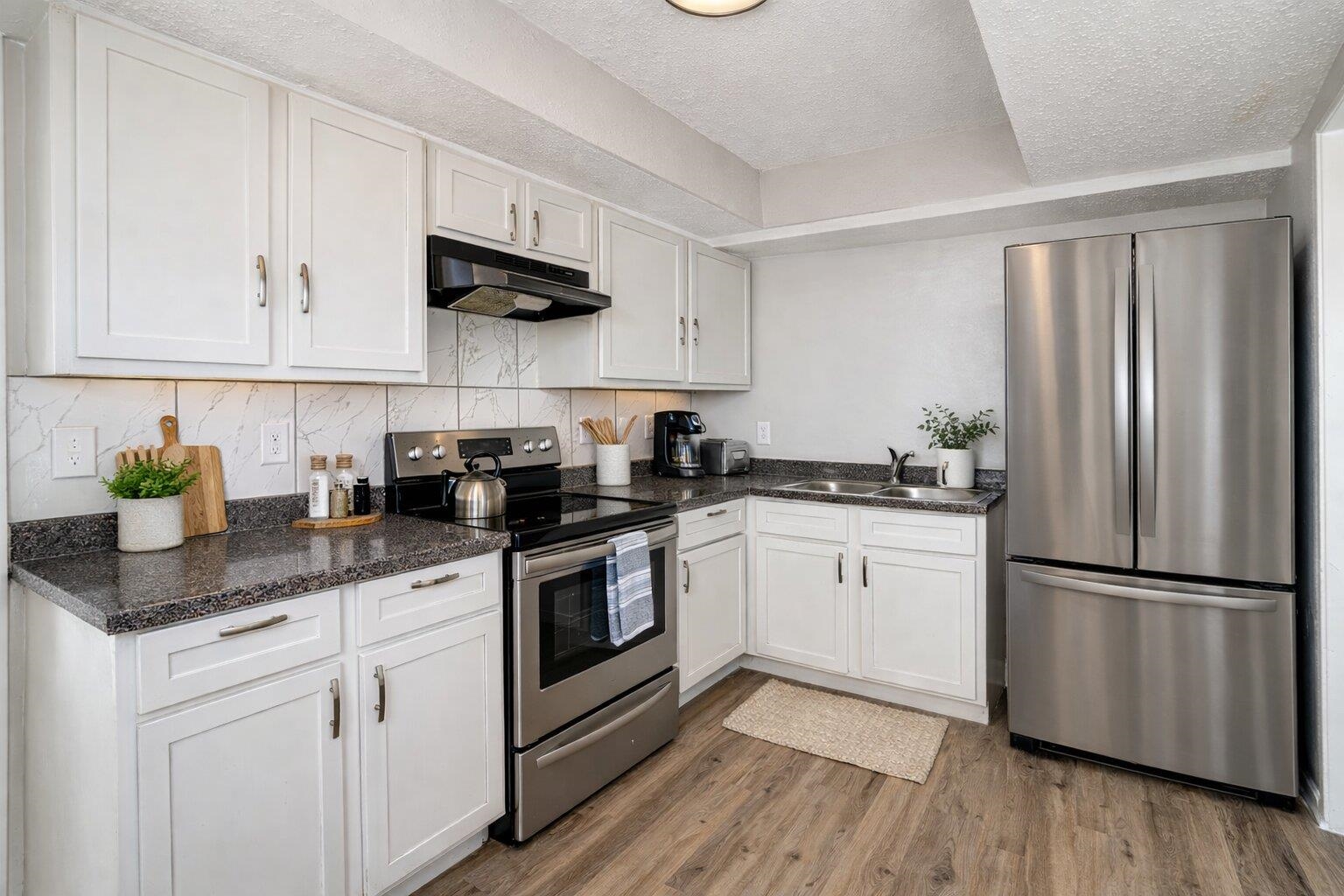 3084 Pershing Avenue Memphis, TN 38112 - Photo 3 of 30 Kitchen featuring stainless steel appliances, white cabinets, light wood finished floors, a textured ceiling, and dark stone countertops