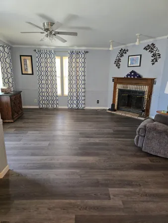 a view of a livingroom with a fireplace a ceiling fan and windows