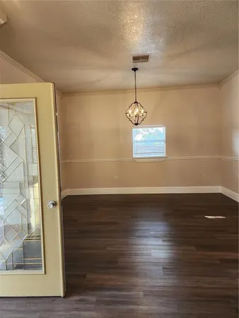 a view of empty room with wooden floor and chandelier