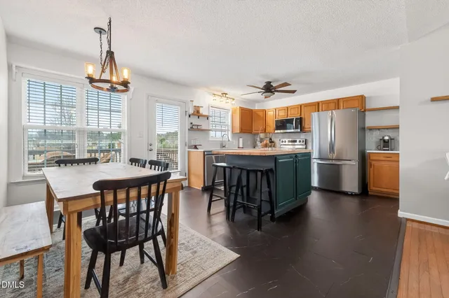 a dining room with stainless steel appliances a table and chairs