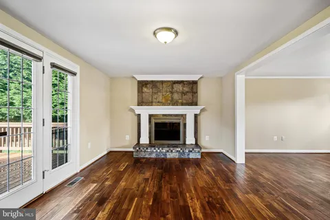 a view of an empty room with wooden floor fireplace and a window