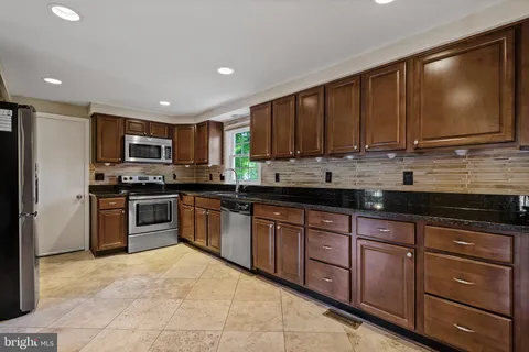 a kitchen with stainless steel appliances granite countertop a stove a sink and a microwave