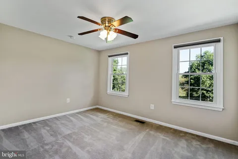 a bathroom with a granite countertop toilet a sink a mirror and a window
