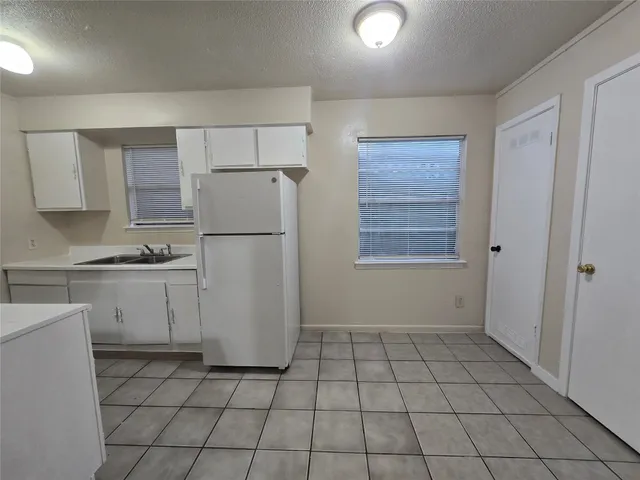a kitchen with a refrigerator a stove top oven and cabinets