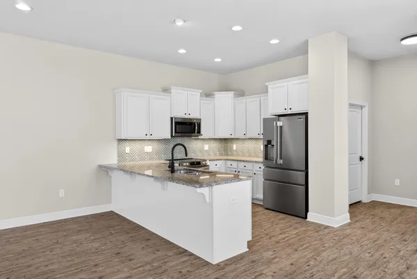 a kitchen with stainless steel appliances granite countertop a refrigerator stove a sink and white cabinets