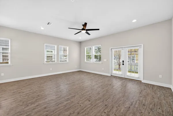 a view of an empty room with a window and wooden floor