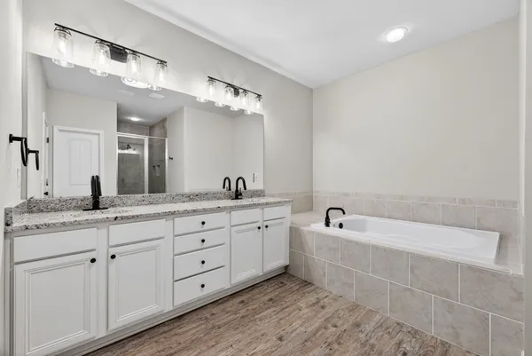a spacious bathroom with a double vanity sink a mirror and a bathtub