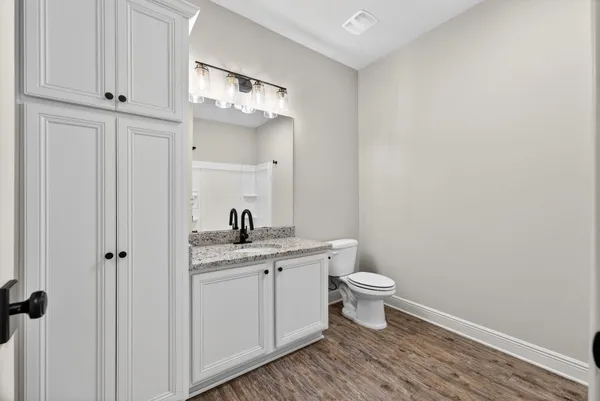 a bathroom with a granite countertop toilet a sink and a mirror