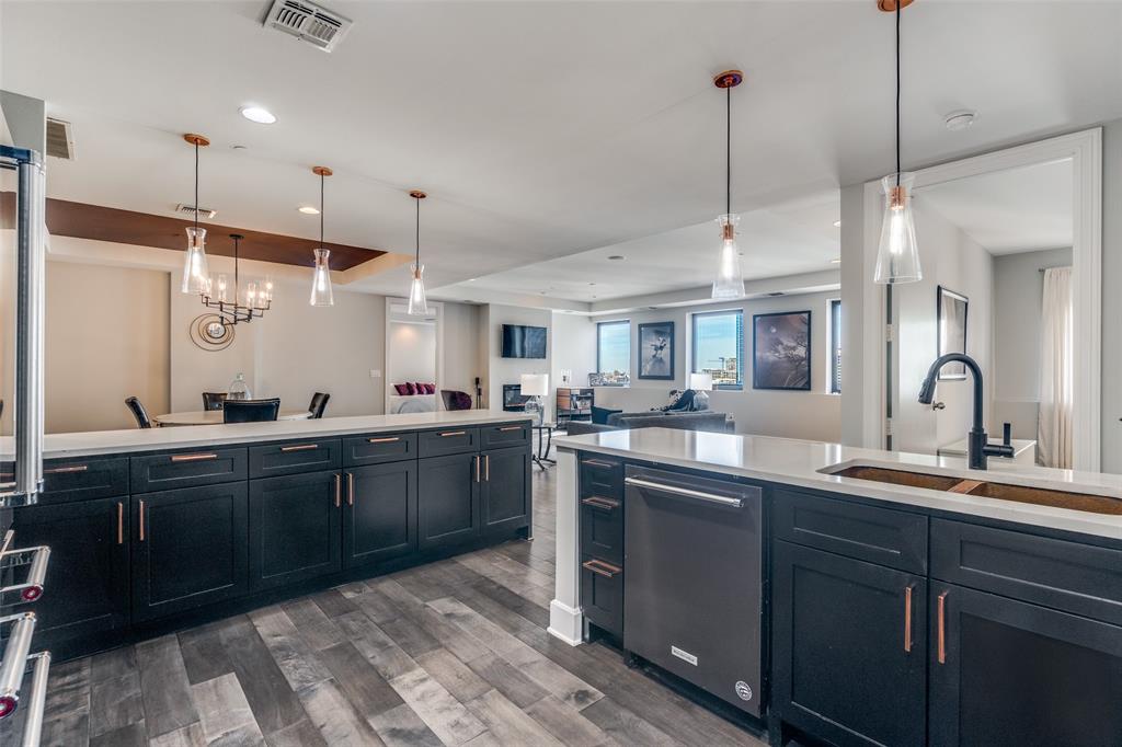 1505 Elm Street, Unit 1504 Dallas, TX 75201 - Photo 32 of 33 Kitchen featuring pendant lighting, stainless steel appliances, dark wood-style flooring, open floor plan, and light stone countertops