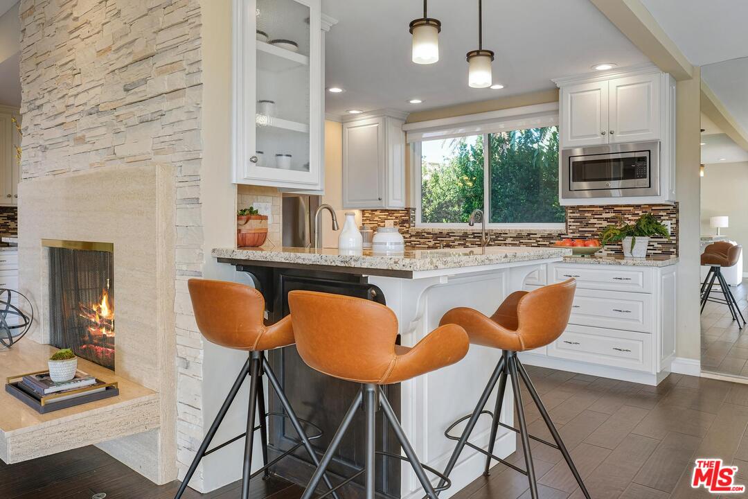 11284 Chalon Road Los Angeles, CA 90049 - Photo 4 of 14 a kitchen with stainless steel appliances kitchen island granite countertop a stove a sink and a dining table with wooden floor