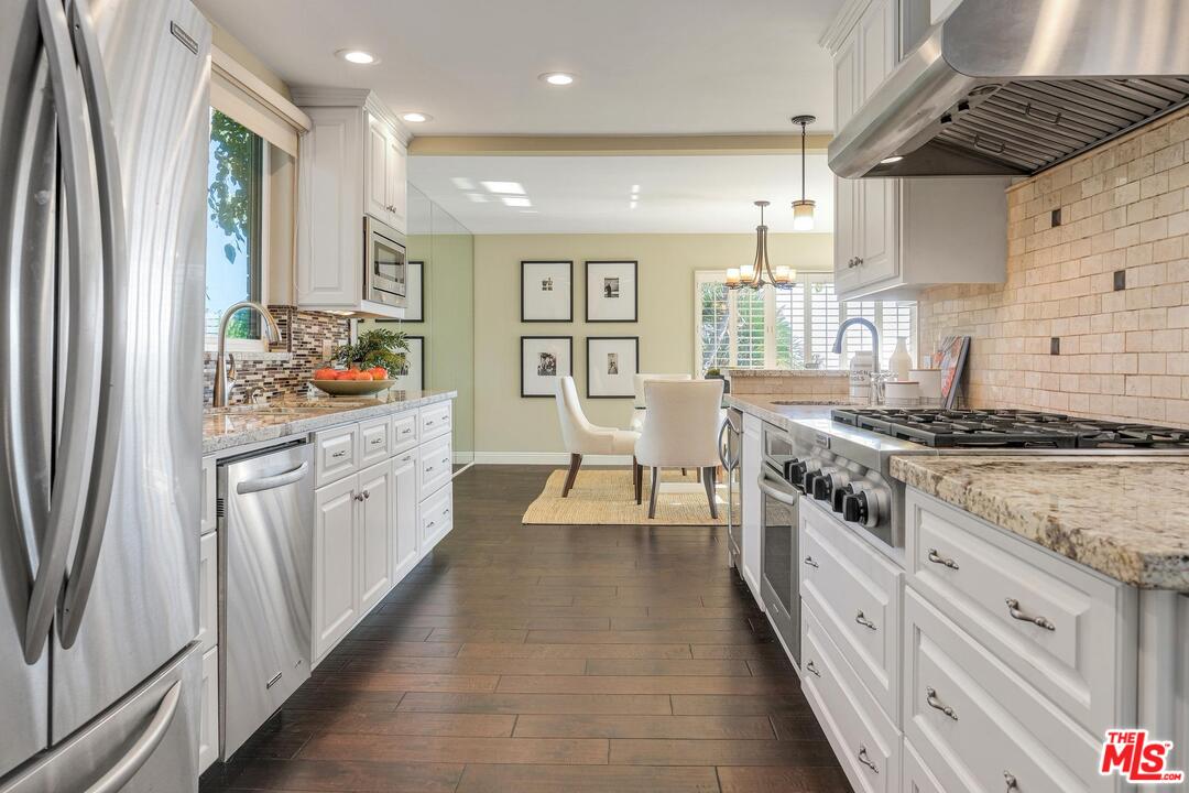 11284 Chalon Road Los Angeles, CA 90049 - Photo 5 of 14 a kitchen with stainless steel appliances granite countertop a stove a sink dishwasher and white cabinets with wooden floor