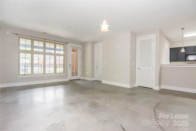 an empty room with a kitchen space and a window