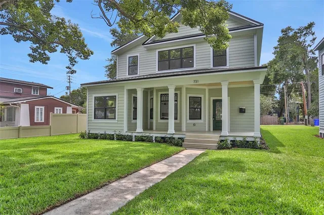 a view of a house with a yard and a large tree