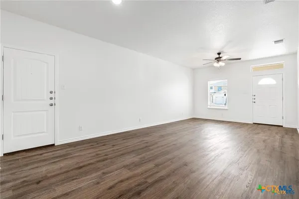 an empty room with wooden floor and windows