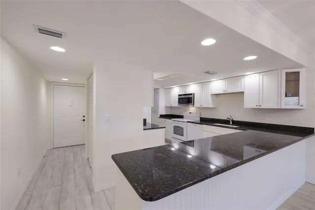 a kitchen with granite countertop white cabinets and white appliances