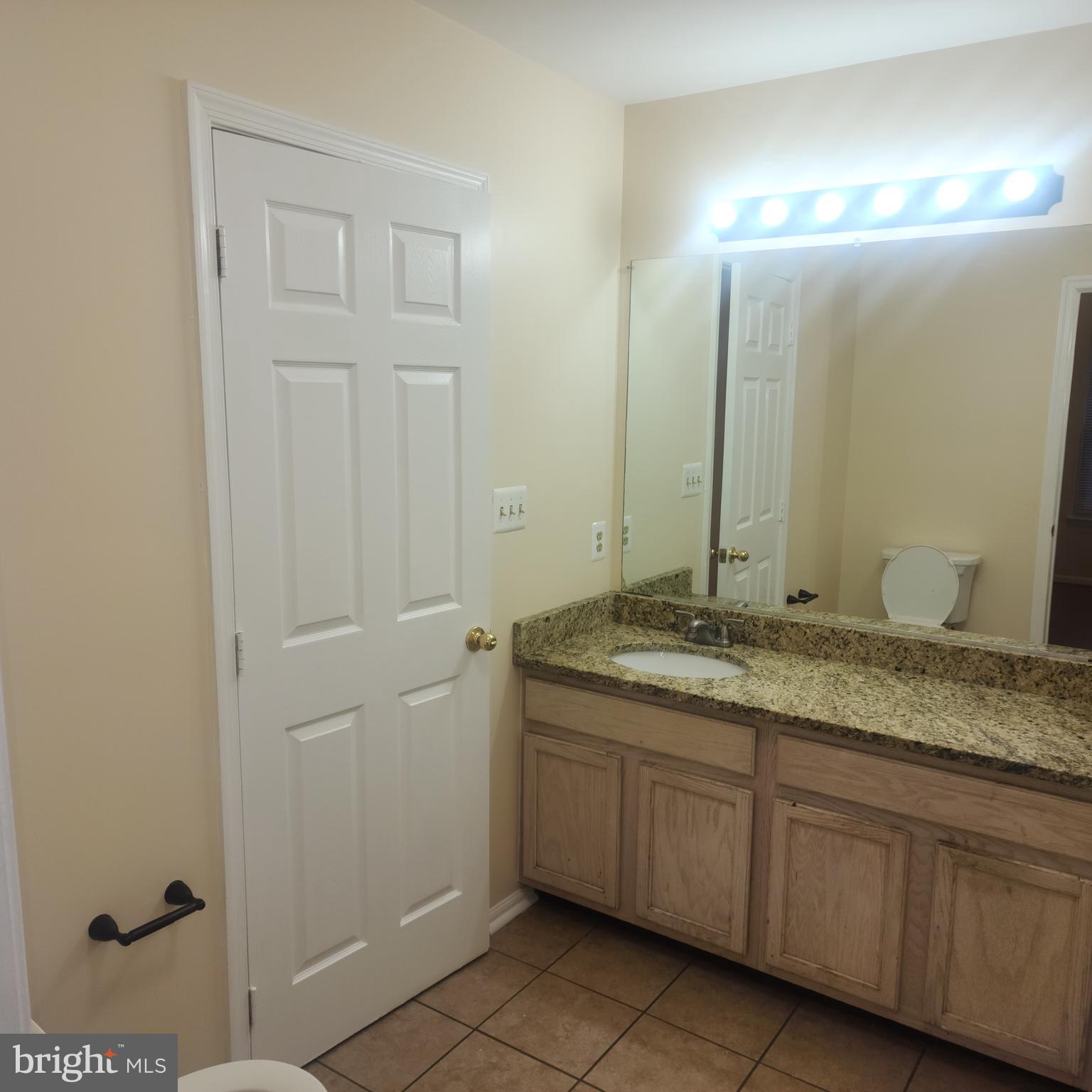 7438 Catterick Court Baltimore, MD 21244 - Photo 19 of 27 a bathroom with a granite countertop sink and a mirror