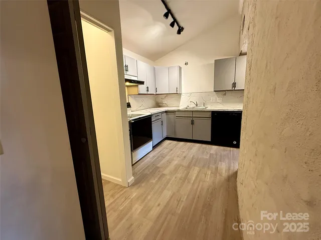 a large white kitchen with granite countertop a sink window and stainless steel appliances